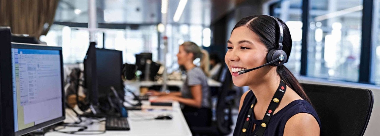 smiling woman takes a call at work while typing at the computer