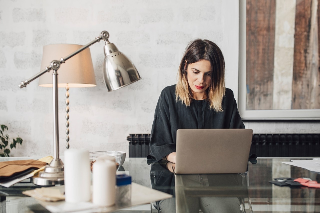 Pretty Caucasian woman sitting at her office deks and working on her laptop.