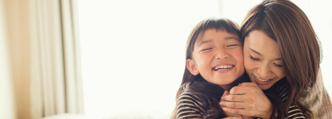 A mother and daughter hugging at home.