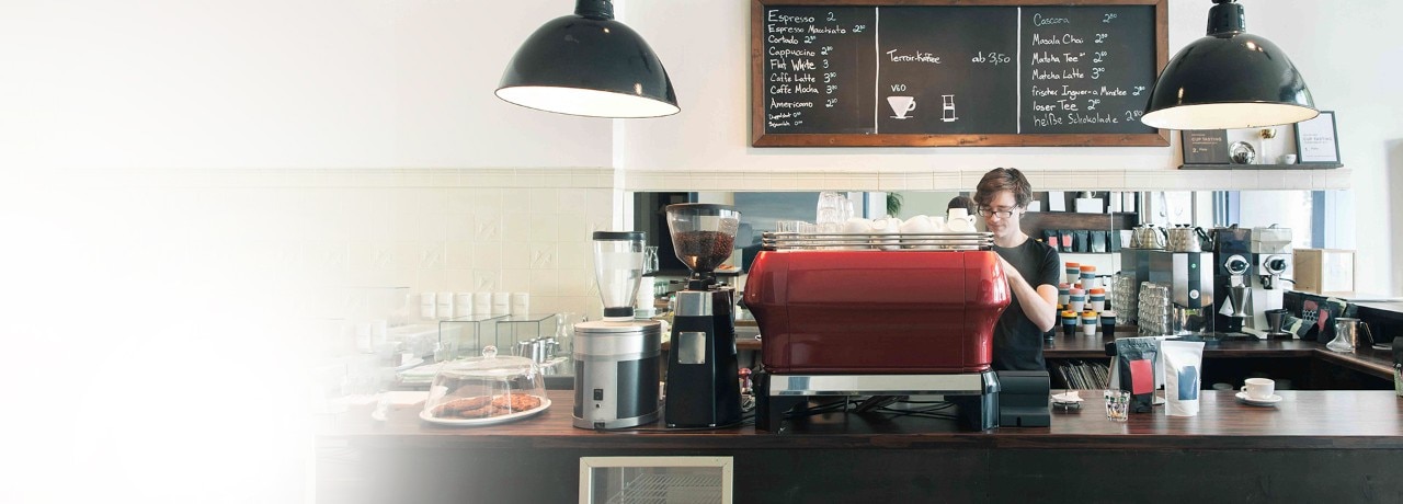 Caucasian barista operating a high-performance coffee machine. Natural light.