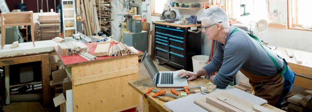 Carpenter working at laptop in workshop