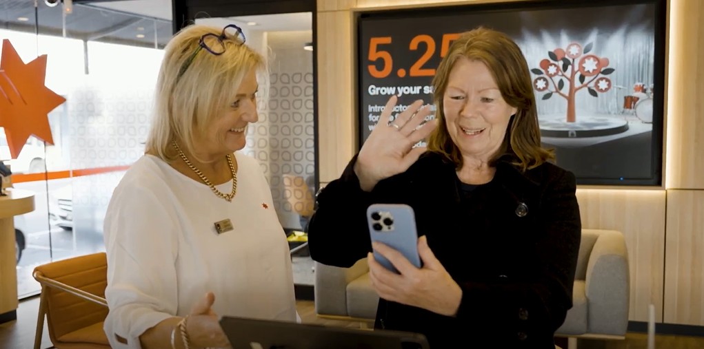 woman conversing with Auslan interpreter on a mobile phone at a NAB branch