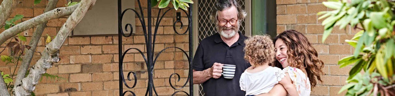 A family smiling outside a suburban family home