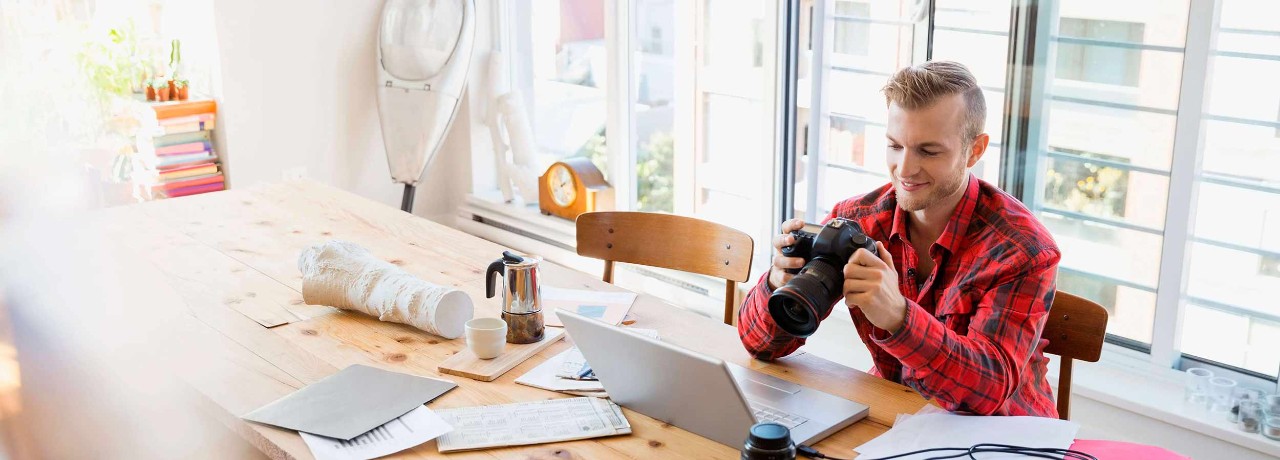 Photographer with camera uploading to laptop at tale