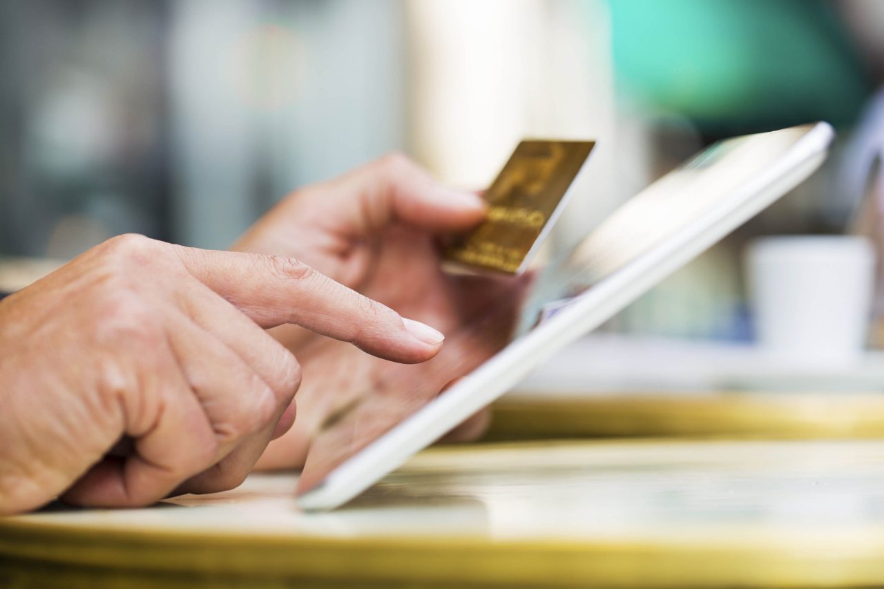 Man holding tablet pc and credit card on coffee terrace