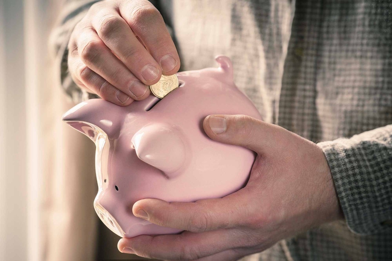 Man inserting coin into piggy bank