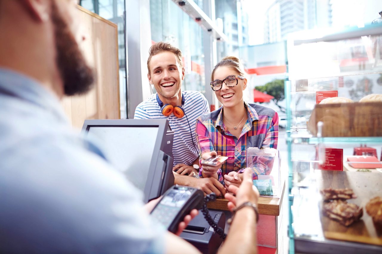 Smiling couple paying worker at cafe counter